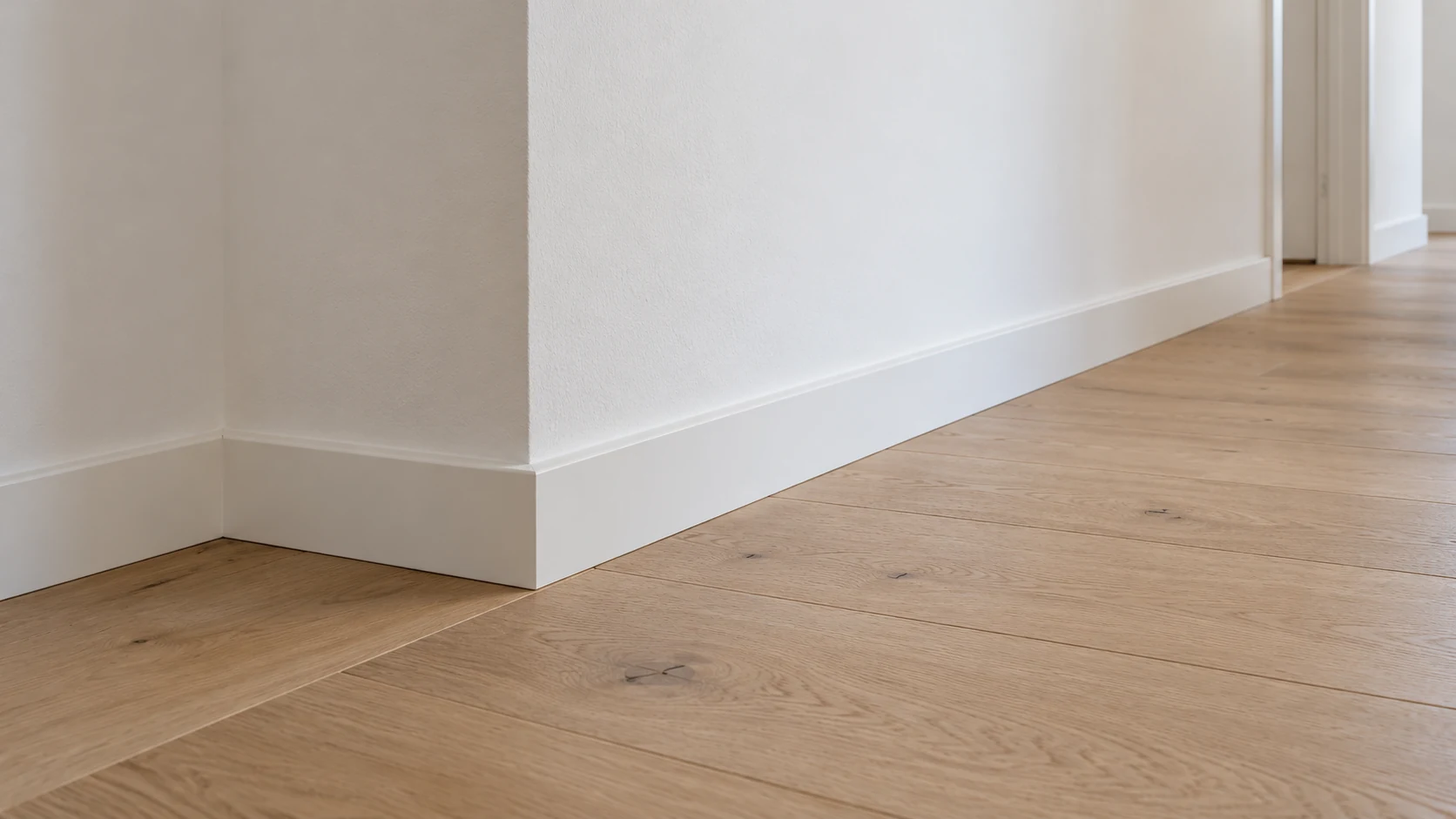 KI-Illustration weißer Sockelleisten an einer hellen Wand mit Innen- und Außenecke auf Eichenboden; verdeckte Befestigung und Wandaufbau sind nicht sichtbar